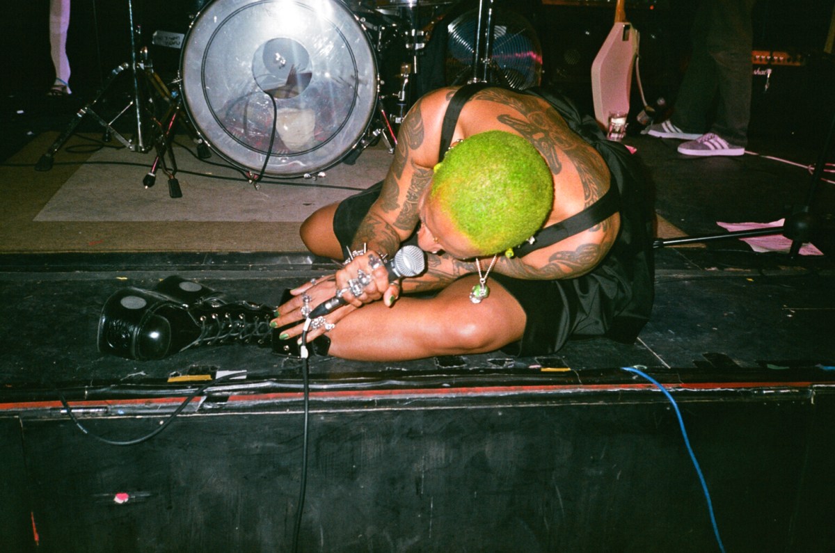 Singer lies on the floor of a stage screaming into a microphone.