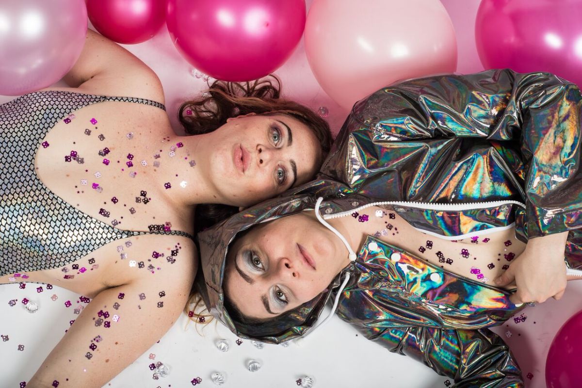 Charmpit lie down on the floor surrounded by pink balloons.